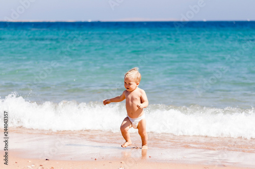 Baby in diapers and hat on the beach - summer joy