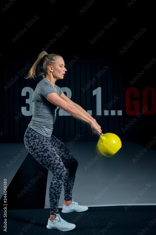 Young woman exercising with kettlebells at the gym. Squats squatting swing WOD fitness gym. Fitness woman workout with kettlebell training at the gym. Photos Adobe Stock