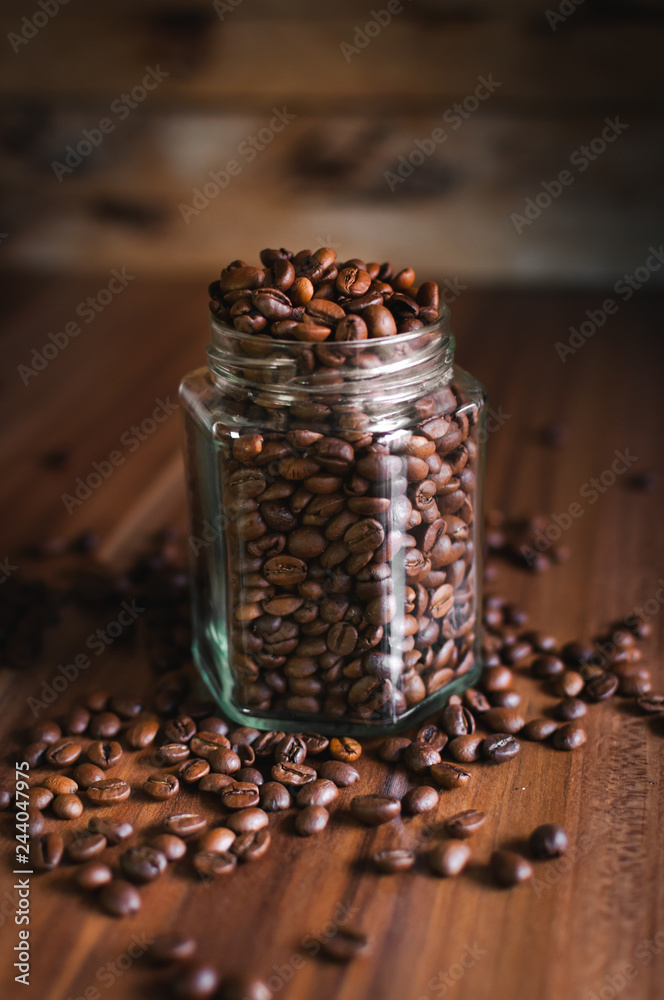Close-up of coffee beans in a glass jar on wooden background Close-up of coffee beans in a glass jar on wooden background