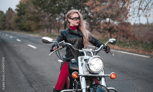 Beautiful biker woman posing outdoor with motorcycle on the road. 
