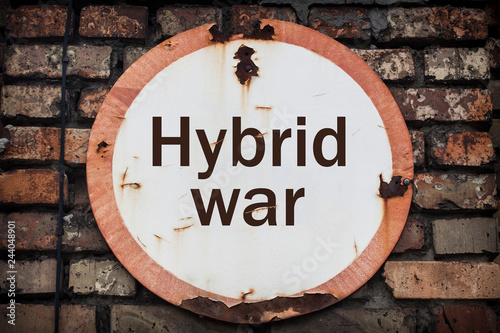 old rusty sign saying Hybrid War on a brick wall photo