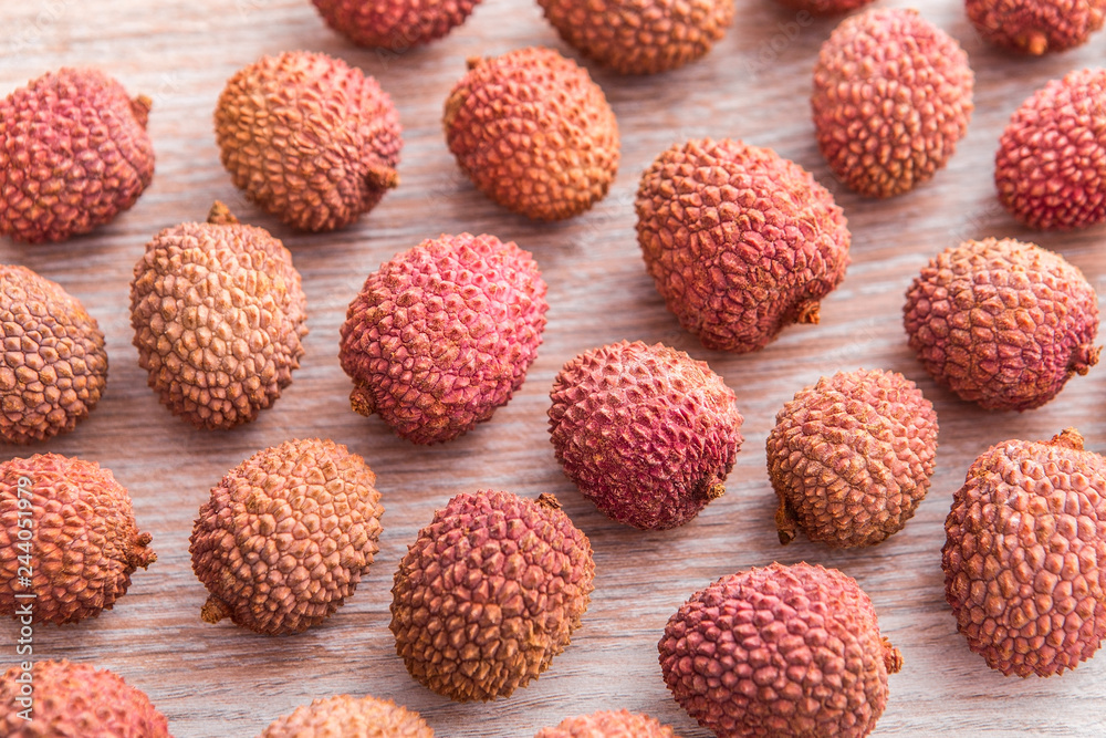Fresh ripe lychee fruit with peel on wooden table
