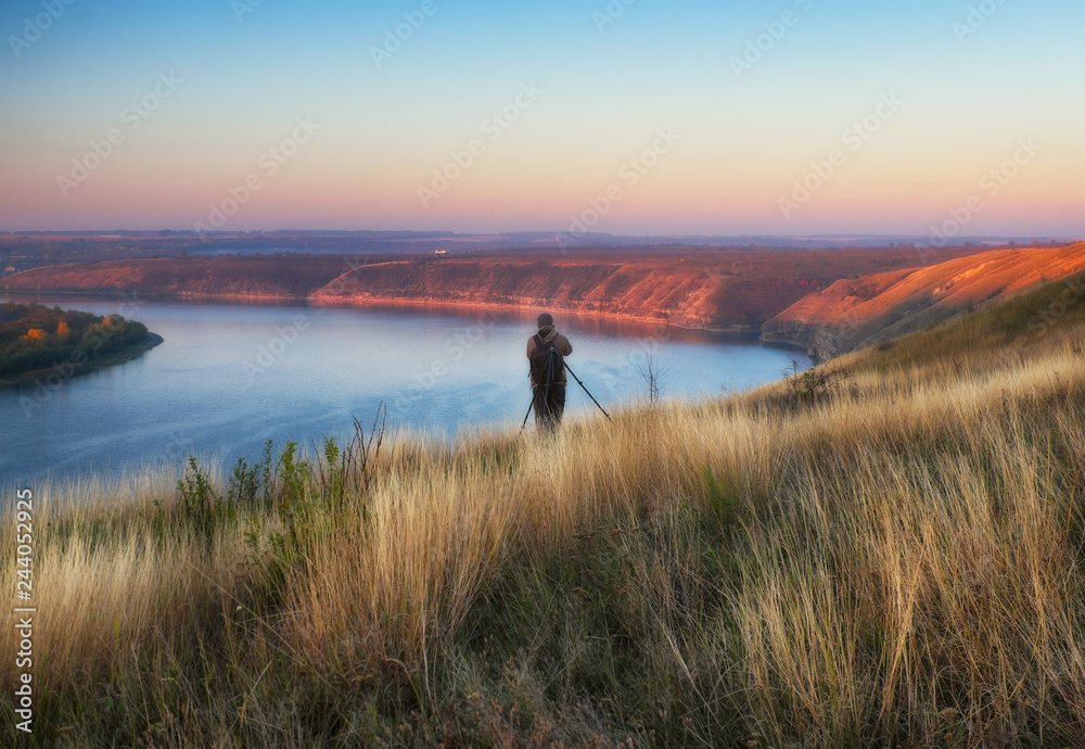 the photographer shoots the canyon of the picturesque river. tourist on the rock. autumn morning
