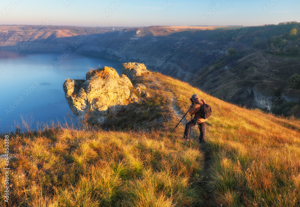 Obraz premium the photographer shoots the canyon of the picturesque river. tourist on the rock. autumn morning 
