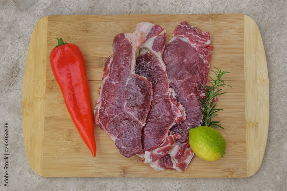 fresh beef meat on a cutting board with lemon and rosemary