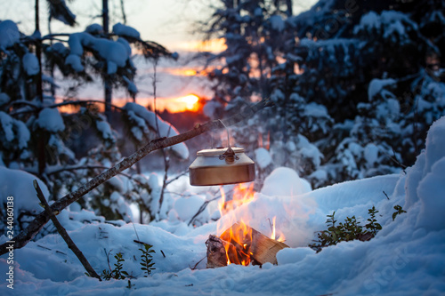 Fireplace and coffee pot in Finland. There is a sunset in the background. There is a lot of snow and frost.