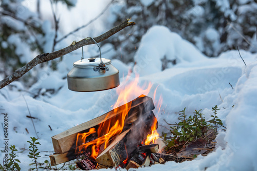 Fireplace and coffee pot in Finland. There is a sunset in the background. There is a lot of snow and frost. photo