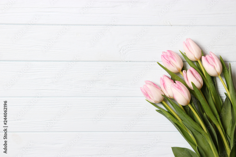 Fototapeta premium A bouquet of tulips on a wooden background top view. Spring background. Background to Mother's Day, International Women's Day, birthday.