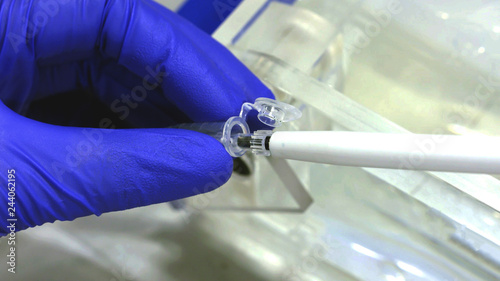 Scientist's hand wearing blue glove using a pipette tool to take a liquid sample, Extreme close up. medical chemistry, biology, and medicine science laboratory concept.