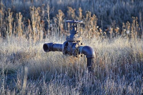 Abandoned rusty irrigation pipe to nowhere against tall grass in the Cradleboard Trail walking path on the Carolyn Holmberg Preserve in Broomfield Colorado by the Rocky Mountains in early spring. Unit photo