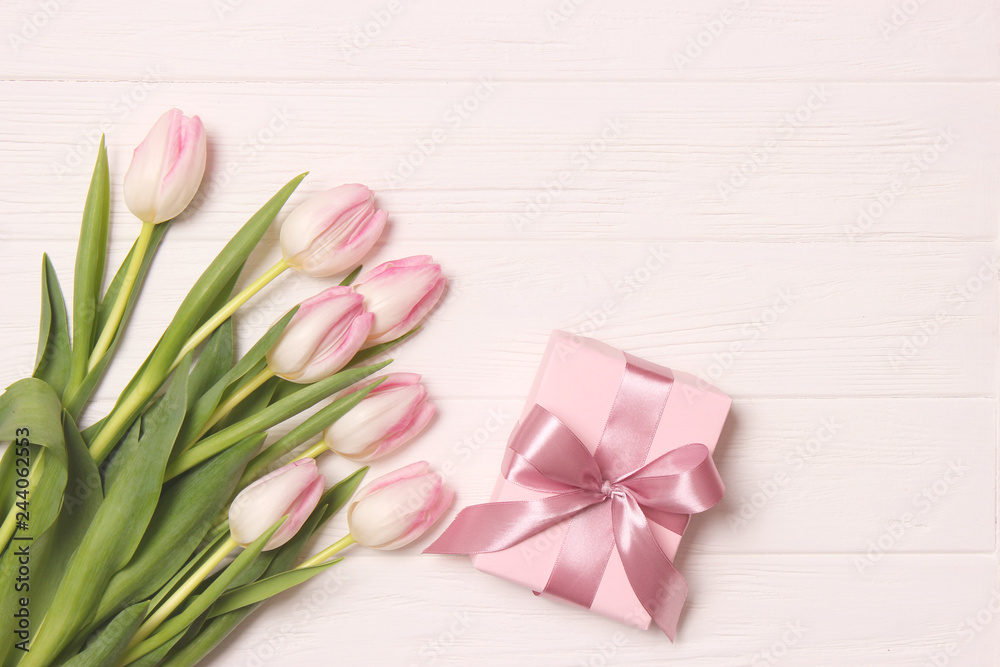 A bouquet of beautiful tulips and a gift on a wooden background top view. Mother's Day Background, International Women's Day. Holiday, give a gift.