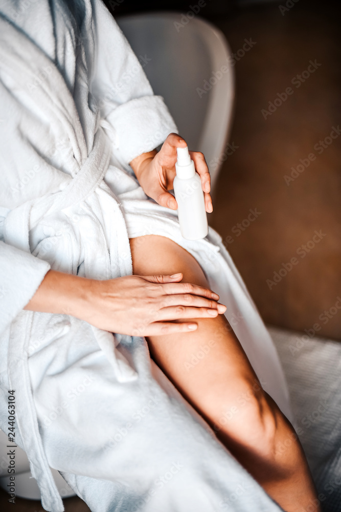 Obraz premium Body care. A young woman in the bathroom applies natural cream to her legs. Against varicose veins and leg edema