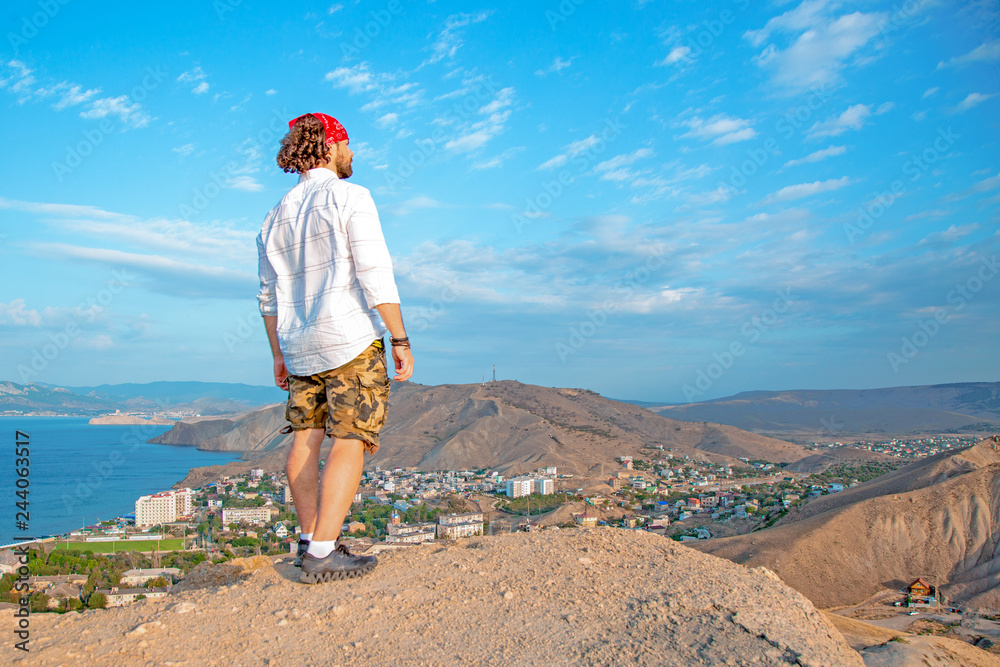 A traveler is standing on the top of a mountain, admiring the scenery A traveler is standing on the top of a mountain, admiring the scenery