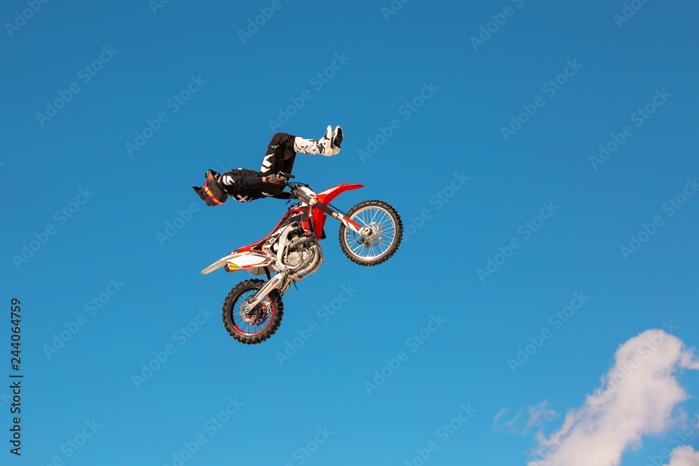 Racer on motorcycle participates in motocross cross-country in flight, jumps and takes off on springboard against sky. Concept active extreme rest. Racer on motorcycle participates in motocross cross-country in flight, jumps and takes off on springboard against sky. Concept active extreme rest.