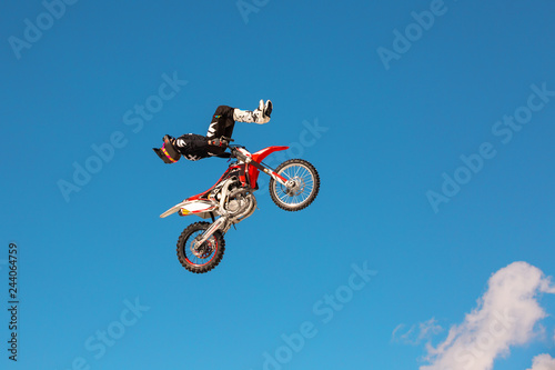 Racer on motorcycle participates in motocross cross-country in flight, jumps and takes off on springboard against sky. Concept active extreme rest.