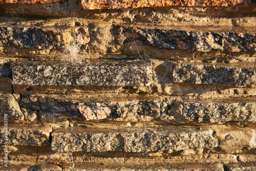 Fragment of a wall of small granite blocks. On the wall a thin layer of water flows. Background