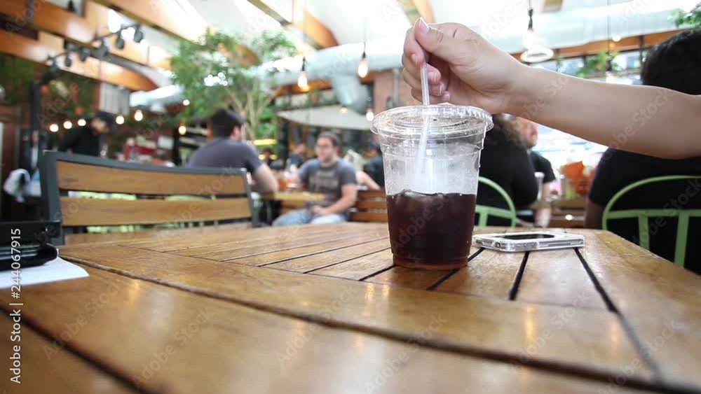 Cola with ice and straw in take away cup on wood table.
