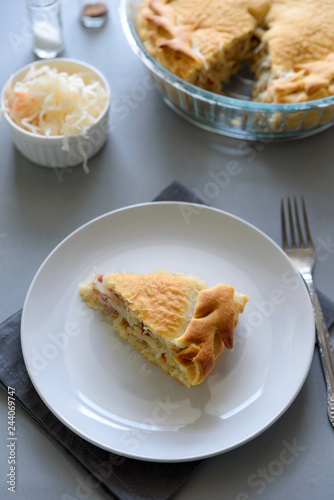 Slice of homemade sauerkraut pie on gray wooden table. Cabbage cake tradition Russian food