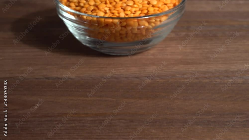 Lentejas naranjas crudas en un bol en la mesa de madera