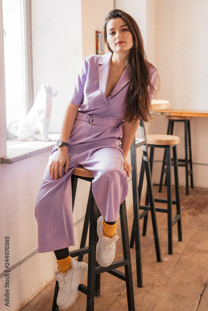 Beautiful sexy young brunette woman with long hair thin slender figure perfect body and pretty face make-up wearing dressed in a stylish violet women's suit with trousers and a jacket Beautiful sexy young brunette woman with long hair thin slender figure perfect body and pretty face make-up wearing dressed in a stylish violet women's suit with trousers and a jacket