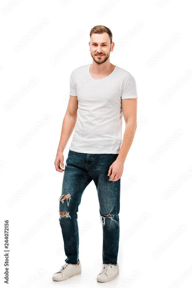 full length view of handsome young man in white t-shirt and jeans smiling at camera isolated on white full length view of handsome young man in white t-shirt and jeans smiling at camera isolated on white