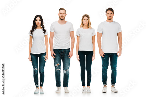 full length view of serious young men and women in white t-shirts and denim pants standing and looking at camera isolated on white photo