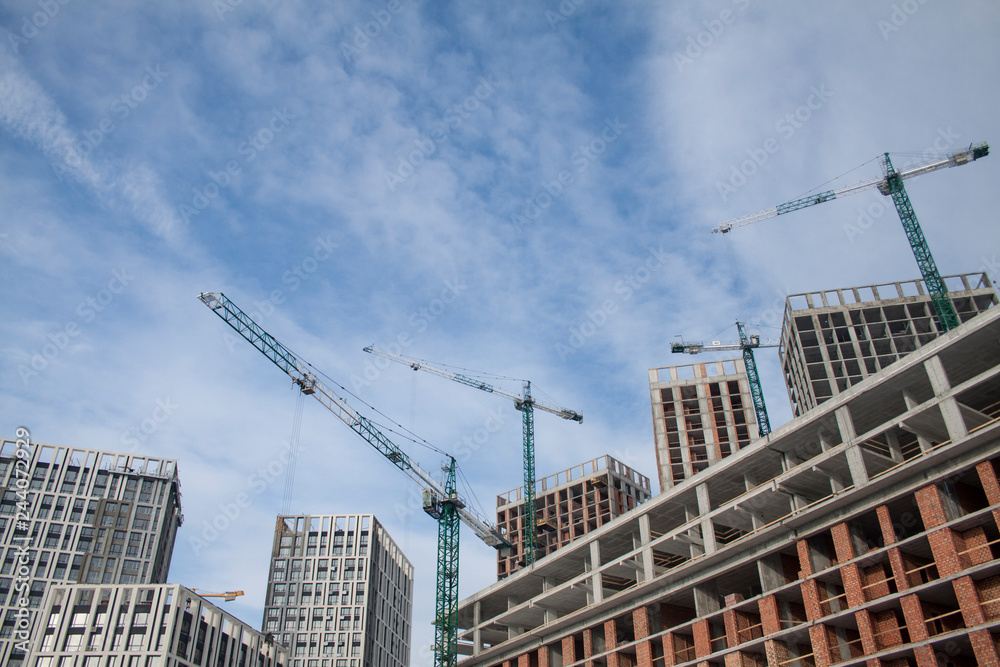 High-rise multi-storey buildings under construction. Tower cranes near building. Activity, architecture, development process, skyscraper