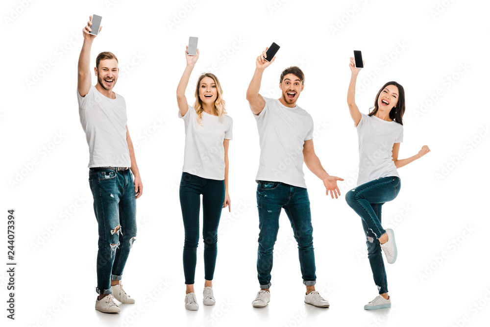 Obraz premium full length view of happy young men and women holding smartphones and smiling at camera isolated on white