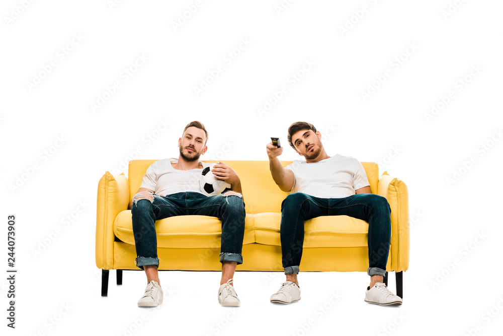 bored men with soccer ball and remote controller sitting on couch and watching tv isolated on white bored men with soccer ball and remote controller sitting on couch and watching tv isolated on white