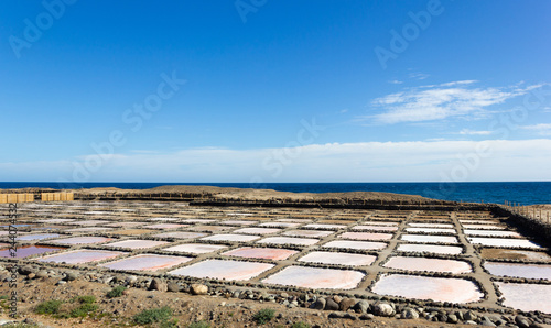 Pozo Izquierdo salt mines at Tenefe cultural park with calm sea on background on sunny day in Gran Canaria, Spain. Saltpans production factory in Canary Islands photo