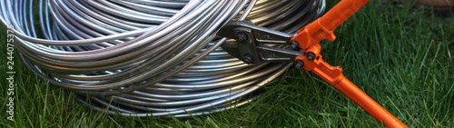 Aluminum wire in the bay on the background of grass, trimmed with a bolt cutter