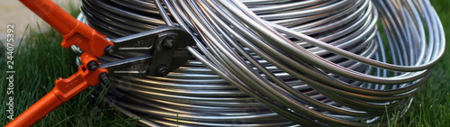 Aluminum wire in the bay on the background of grass, trimmed with a bolt cutter