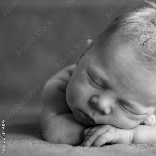 A newborn baby sleeping on his stomach, put his hands under his head. Toned