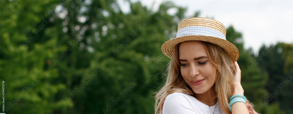 Girl blonde in a straw hat in a city park. Romantic mood. Smile, emotion, state of mind