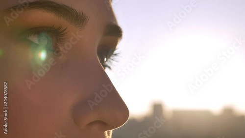 Closeup portrait of young beautiful female eyes looking forward. Woman in hijab with sun shining on the background