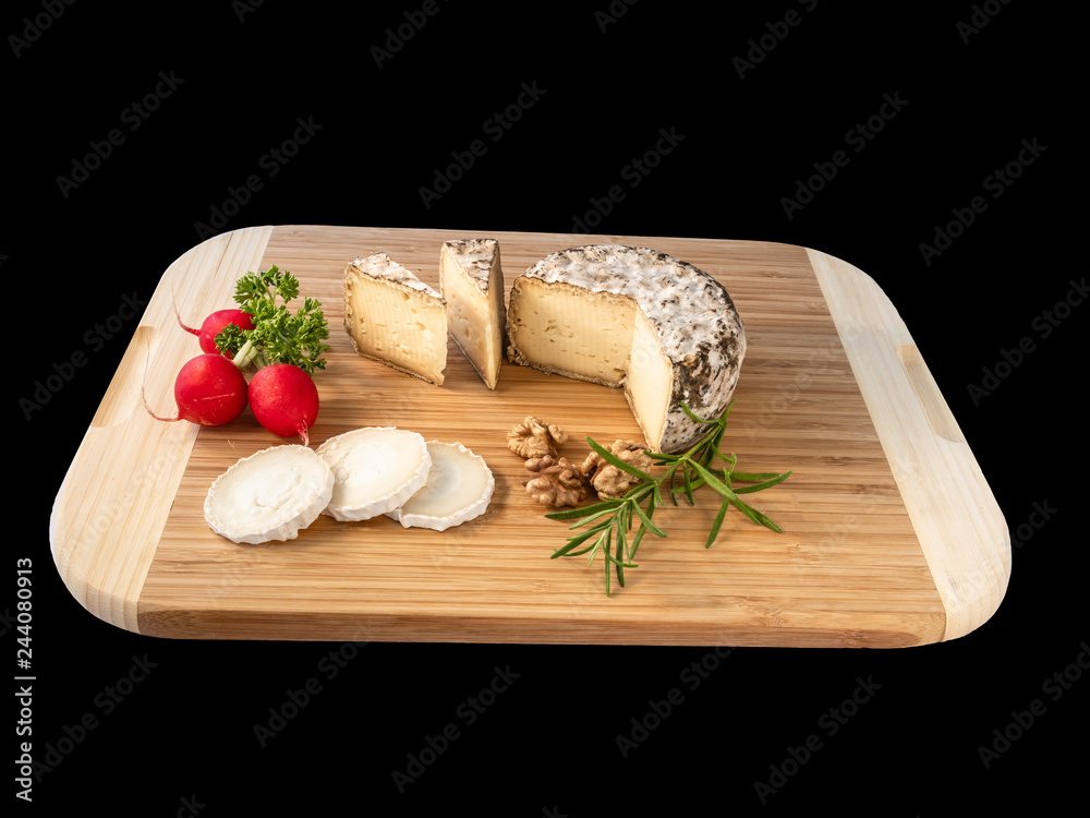 Cheese from France named Tommette des Alpes and white round goat cheese with nuts and parsley on the black background with shadow Cheese from France named Tommette des Alpes and white round goat cheese with nuts and parsley on the black background with shadow