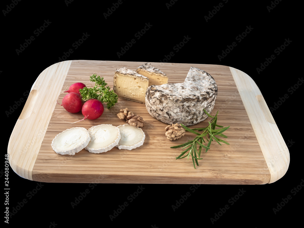 Cheese from France named Tommette des Alpes and white round goat cheese with nuts and radish and parsley on the black background with shadow Cheese from France named Tommette des Alpes and white round goat cheese with nuts and radish and parsley on the black background with shadow
