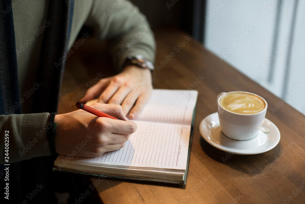 Young man sitting in coffee shop and writing Young man sitting in coffee shop and writing