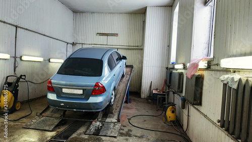 Car lifted in automobile service for fixing, worker repairs detail.