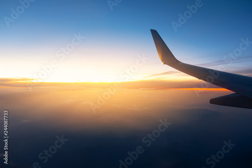 Airplane wings in the sky and a mountains view scene in the sunrise. Travel and adventure.