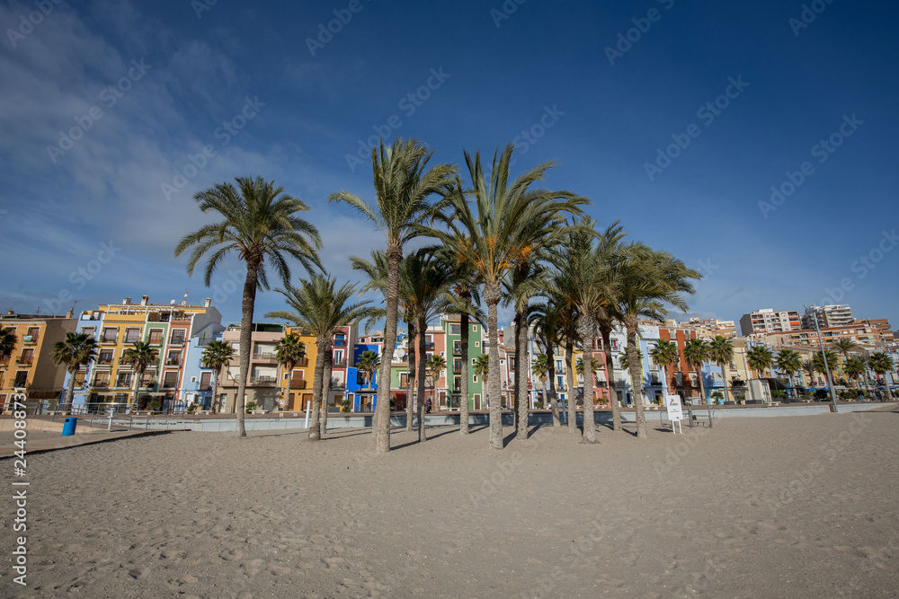 Joiosa, Alicante, Spain - 26 december 2017: View on the houses at the beach of the village Joiosa, Alicante, Spain with palms trees in front Joiosa, Alicante, Spain - 26 december 2017: View on the houses at the beach of the village Joiosa, Alicante, Spain with palms trees in front