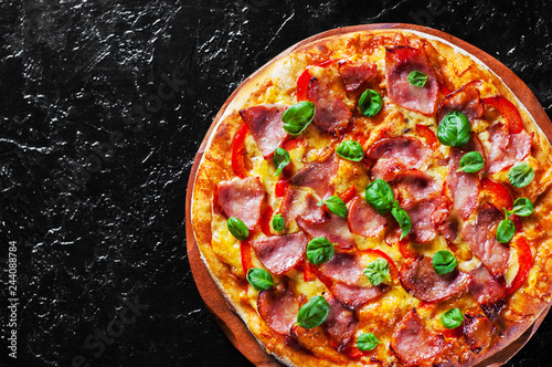Pizza with Mozzarella cheese, ham, pepper, meat, Tomato sauce, Spices and Fresh Basil. Italian pizza on black background