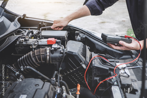 Services car engine machine concept, Automobile mechanic repairman hands repairing a car engine automotive workshop with a wrench and digital multimeter testing battery, car service and maintenance