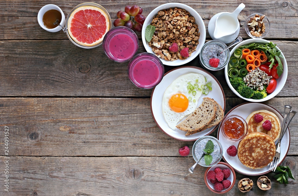 Brunch or breakfast table. Festive brunch set, meal variety with quinoa salad bowl, fried egg, granola, pankes, chia seeds pudding and smoothy . Overhead view Brunch or breakfast table. Festive brunch set, meal variety with quinoa salad bowl, fried egg, granola, pankes, chia seeds pudding and smoothy . Overhead view
