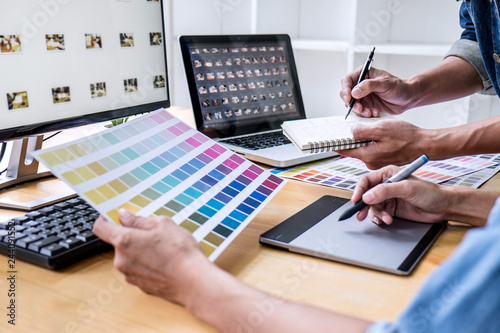 Two colleagues creative graphic designer working on color selection and drawing on graphics tablet at workplace, Color swatch samples chart for selection coloring