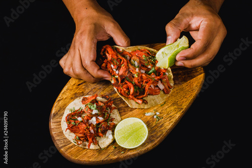 Tableau sur toile Tacos al pastor flat lay on a black background, with a person squeezing lime on it