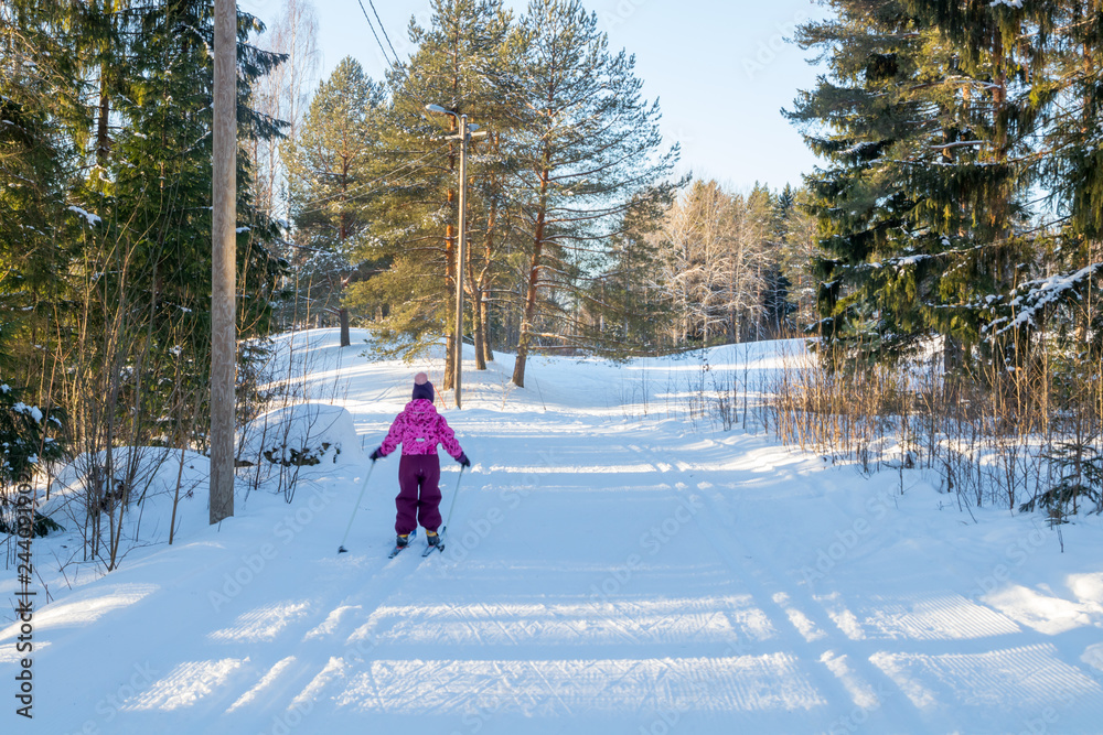 Naklejka premium Small child in the ski track at winter forest in Finland.