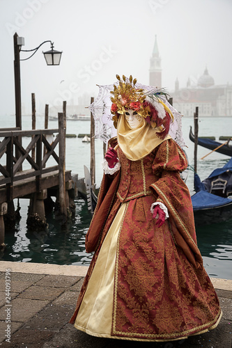 Woman in Venetian carnival outfit on the lagoon background