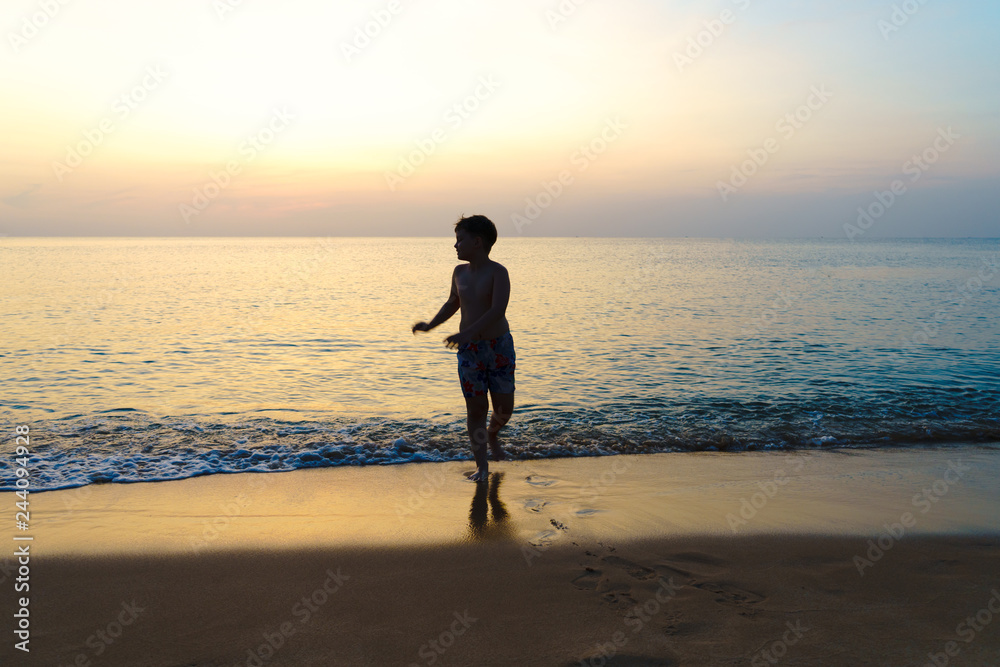 little boy running on the beach at sunset