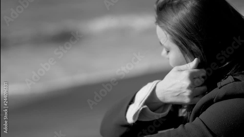 Sad lonely woman sitting in front of the ocean thinking slow motion closeup
